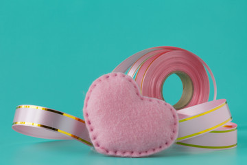 Pink ribbon and heart on pink background.