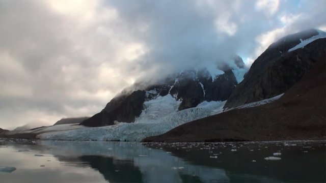 Moving Ice Floes on background of mountain on water of Arctic Ocean in Svalbard. Wildlife in Nordic badlands. Unique footage on background natural landscape and snow of Spitsbergen.