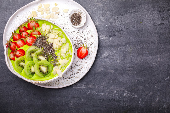 Breakfast Detox Green Smoothie  Bowl with fresh berries,kiwi and chia seeds. Food or Healthy diet concept on the gray background.Super Food.selective focus.