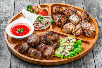 Roasted Pork steak on bone stuffed with cheese, grilled vegetables and berries on stone slate background on wooden background close up. Hot Meat Dishes. Top view with copy space