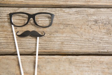 Overhead view of eyeglasses and mustache on table