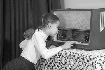 Little girl listens to old radio.