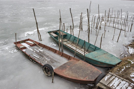 Two old wooden boat, one wrecked in a frozen river Tisa near Becej, Serbia. Winter time