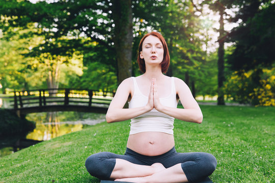 Beautiful pregnant woman doing prenatal yoga on nature outdoors.