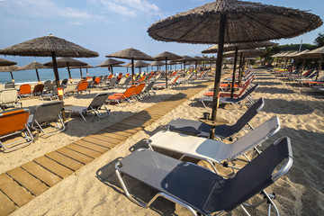 Beautiful Ionian sandy beach in Greece with with sunbeds and straw sunshades, umbrellas. Vacation destination