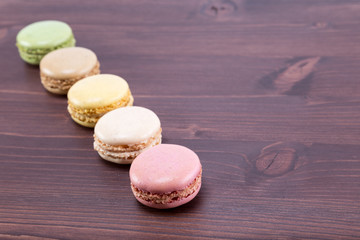 Five tasty and colorful macaroons on a natural ipe wood dark brown table
