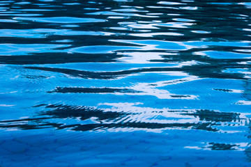 Reflection of sky on the moving water surface in the pool