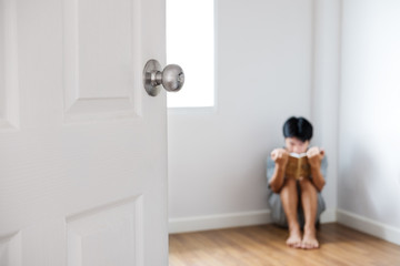 Door opened with blur nerd Asian guy reading a book in corner of the room