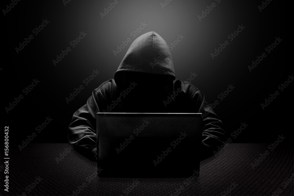 Wall mural hooded computer hacker stealing information with laptop