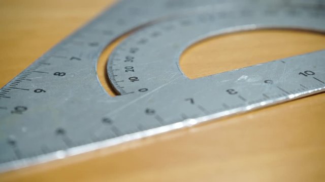 Old metal protractor ruler and set square on wooden  table background, dolly shot 4K ProRes HQ codec