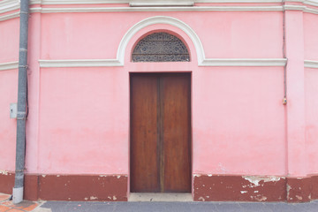 An old wood door on pink wall.