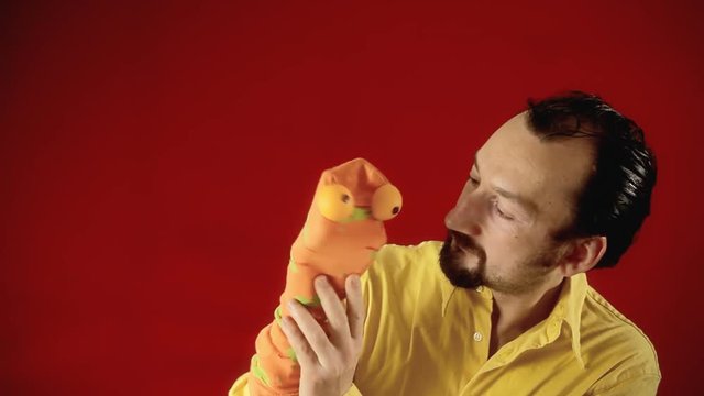 A funny man playing with a handmade sock puppet trying to kiss him.
