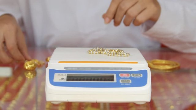 digital scales for weighing gold rings and necklaces with hand in store