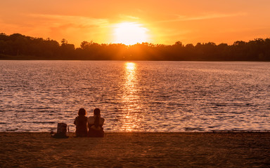 Friends and families are picnicking under sunset of a lake	