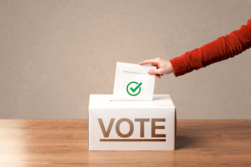 Close up of male hand putting vote into a ballot box