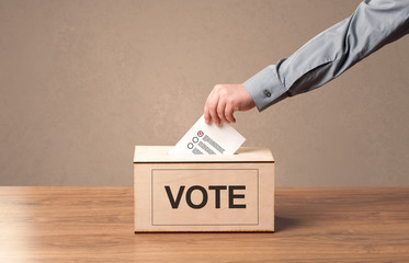 Close up of male hand putting vote into a ballot box