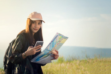 women asian with bright backpack looking at a map. View from back of the tourist traveler on background mountain, Female hands using smartphone, holding gadget