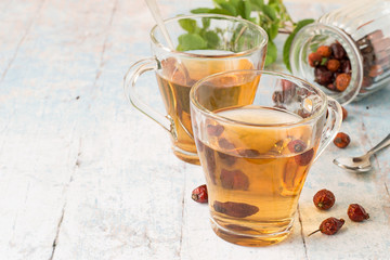 
  Freshly prepared infusion of dry fruit rose hips in glass transparent mug on a light wooden background.
