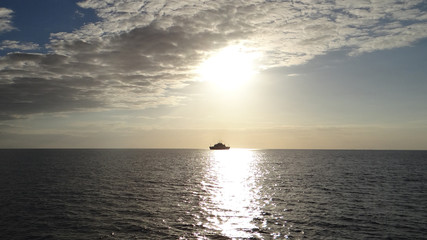 Naklejka na ściany i meble A ferry heads toward Cozumel from the mainland of Mexico. The sun is setting in the Caribbean Sea.