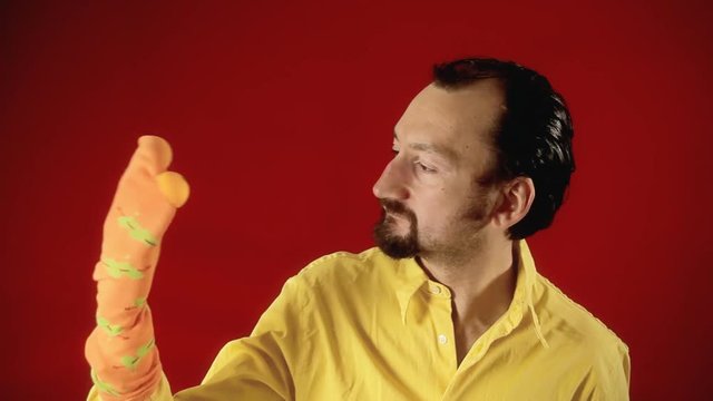 A grownup man plays with a handmade sock puppet and is surprised by another one appearing behind him.

