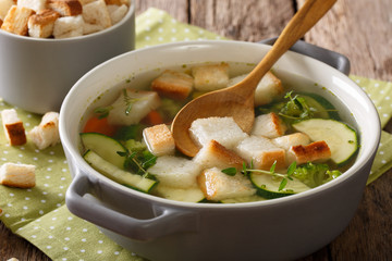 Light vegetable broth with croutons and thyme close-up in a saucepan. horizontal