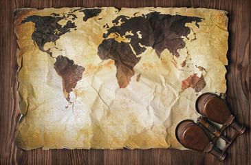 Old map of the world on yellow retro stained paper with vintage binoculars