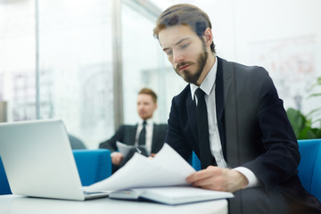 Serious economist looking through financial papers at workplace