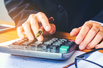 Fototapeta premium Businessman's hands with calculator at the office and Financial data analyzing counting on wood desk