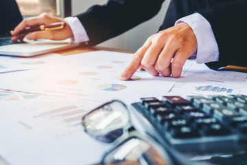Businessman's hands with calculator at the office and Financial data analyzing counting on wood desk