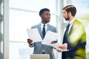 Two economists with papers having conversation