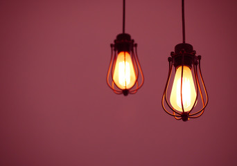 Illuminated hanging light bulbs on pink plain background with free text space