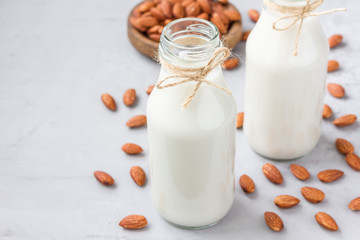 Almond milk in bottles with almonds on background, horizontal, copy space
