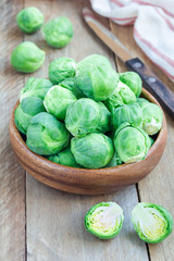 Fresh brussels sprouts in bowl on wooden background, vertical