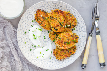 Vegetarian quinoa, carrot, coriander and green onion fritters served with yogurt on plate, horizontal, top view