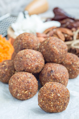 Healthy paleo energy balls with carrot, nuts, dates and coconut flakes, on parchment, vertical
