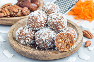 Healthy homemade paleo energy balls with carrot, nuts, dates and coconut flakes, on wooden plate,...