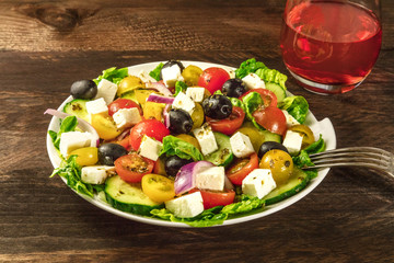 Greek salad with feta, fresh vegetables, and rose wine