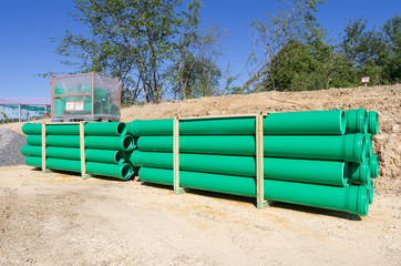 pallets of green sewer pipes at construction site