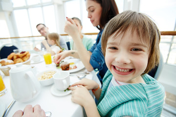 Adorable boy looking at camera during family breakfast
