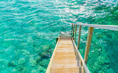 Wood stair into the sea of tropical Maldives island .