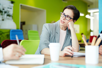 Portrait of confident businesswoman talking to partners at meeting table