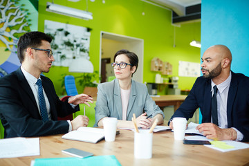 Group of modern business people discussing work during meeting in contemporary creative agency
