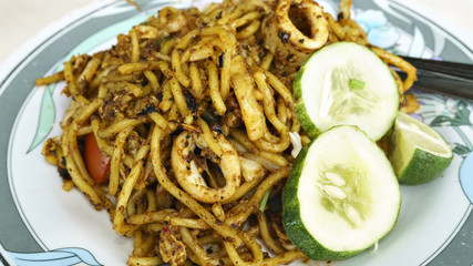 Mee Goreng with sliced cucumber and lemon on the plate