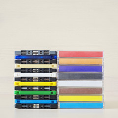 Stack of old colorful dirty audio cassettes and cases on the brown wooden shelf - 156893268
