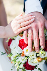 Obraz na płótnie Canvas Жених и невеста держат руки на фоне свадебного букета из роз, эустомы и лилии