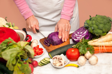 Woman cutting red cabbage on slices in the kitchen