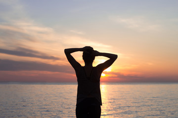 fitness mixed race woman silhouette in yoga pose on the morning beach, beautiful fit woman practice fitness exrxise stones, morning sea or ocean background