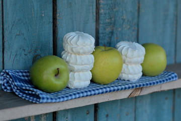 Белый зефир и зелёные яблоки на голубом фоне