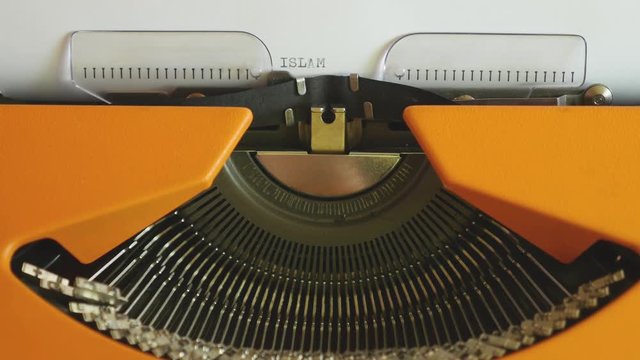 High angle footage of a person writing ISLAMOPHOBIA on an old typewriter, with sound...