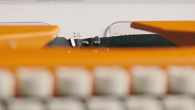 Low angle footage of a person writing ISLAMOPHOBIA on an old typewriter, with sound
